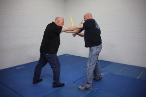 Image of a man with a knife stopping an attack by a man with a bat