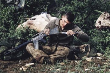 soldier using knife to clean gun