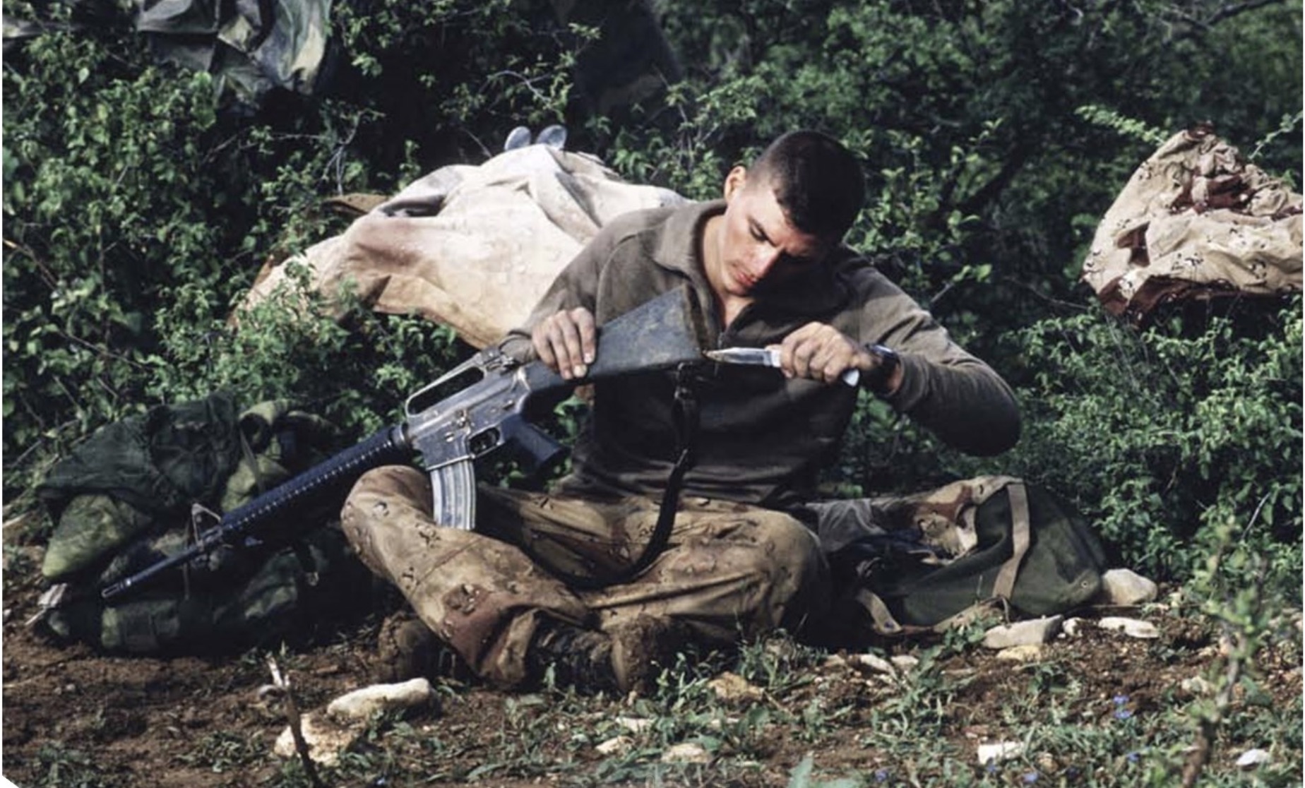 soldier using knife to clean gun