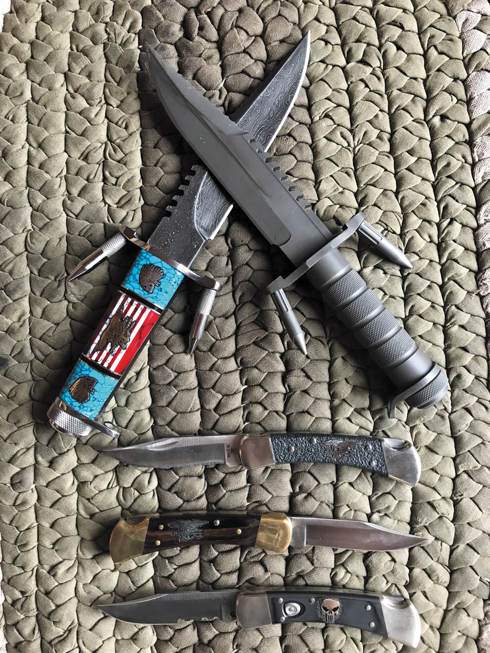 Top-left is the David Yellowhorse Damascus 184, top-right is the CMDR Coulter all-titanium 184. Below, David made two SEAL Trident 110s and a Punisher 110 auto.