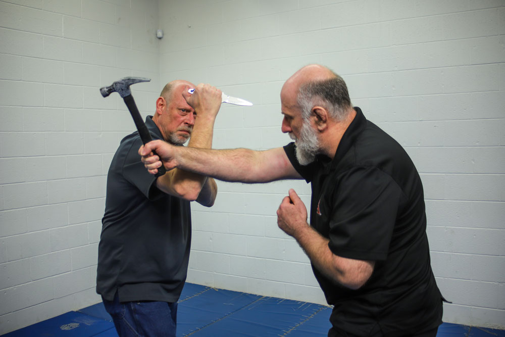 The dagger-armed defender first executes a two-step Hubud parry from the Filipino martial arts to deflect the strike