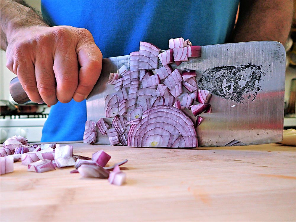 The author displays cleaver techniques for dicing an onion for making chili.